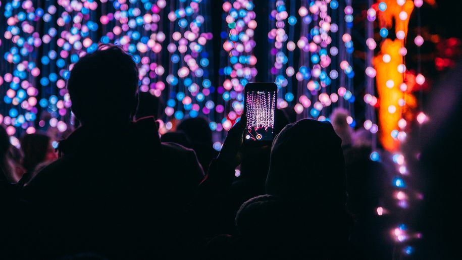 Person taking a photograph of Christmas lights.
