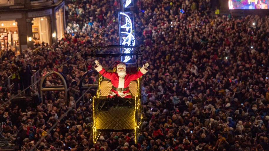 Father Christmas flying in his sleigh over a crowd