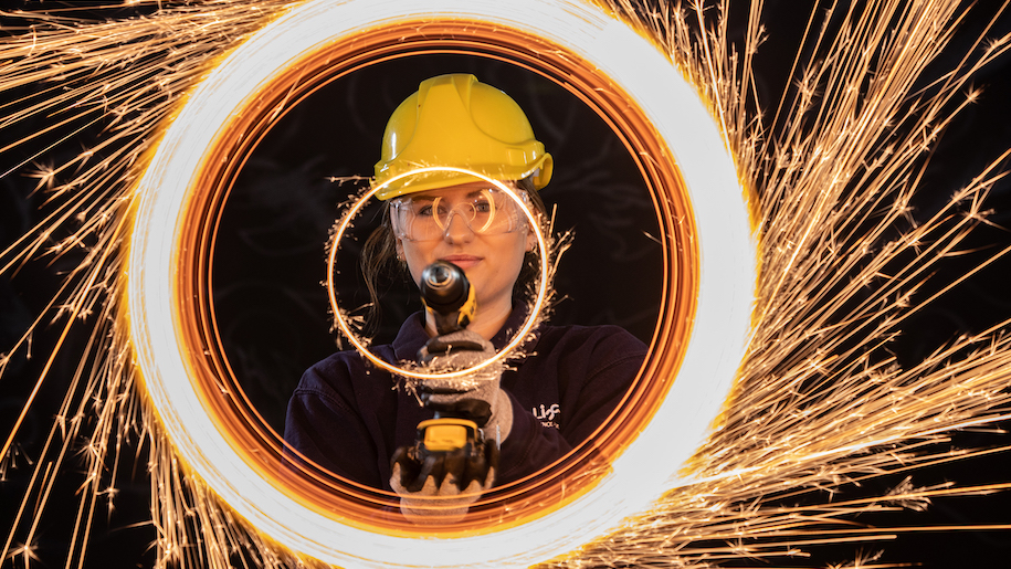Sparks flying off wheel with woman wearing yellow hat