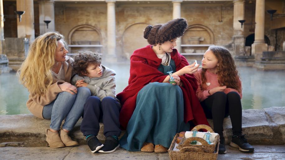 Family with lady in costume at Roman Baths in Bath