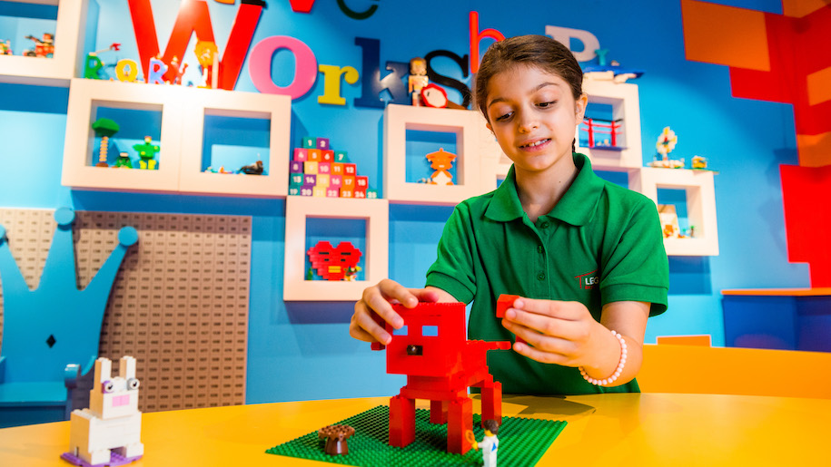 Girls building red dog with Lego bricks