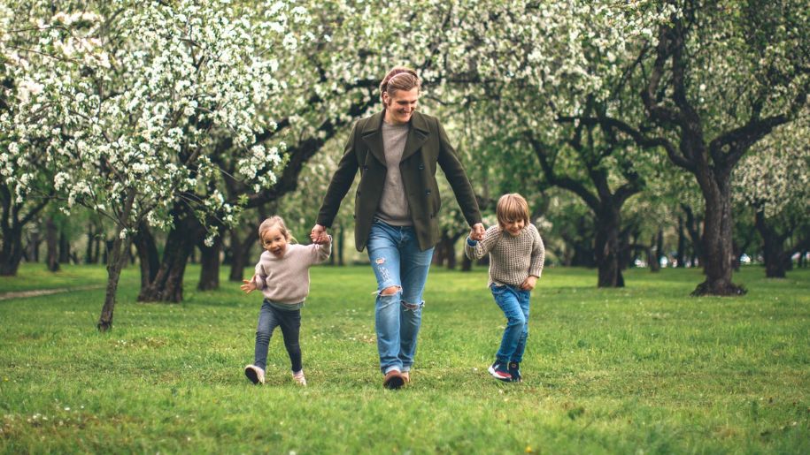 Adult and young children walking through an orchard.