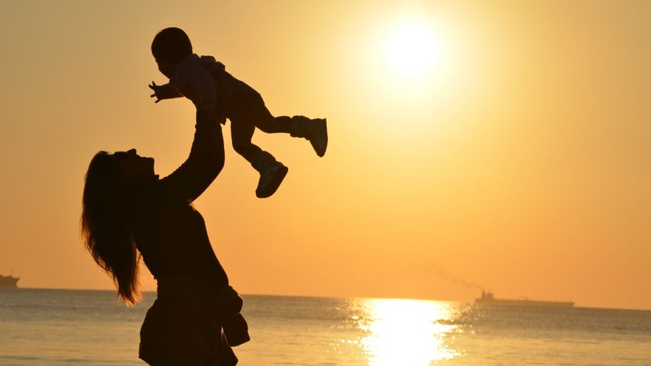 Adult and child silhouetted against the setting sun.