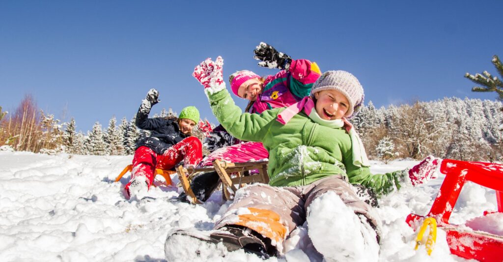 kids in colourful clothing on a ski slope with blue sky