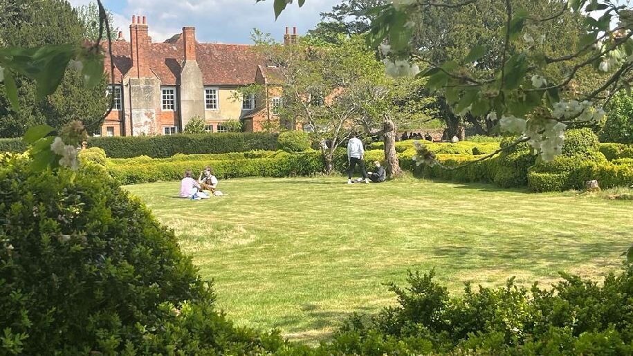 West Horsley Place People sitting and standing in garden with house in background