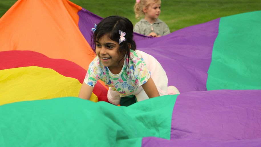 Girl playing in colourful parachute at Ultimate Activity Camps