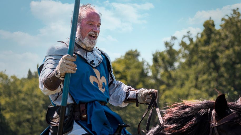 A man dressed as a medieval knight on a horse for historical reenactment.