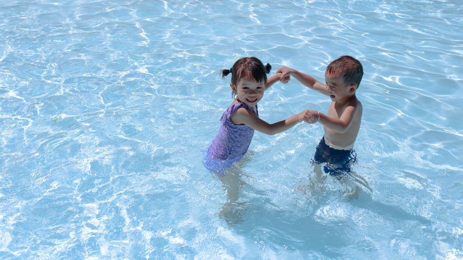 Two young children having fun in a swimming or paddling pool.