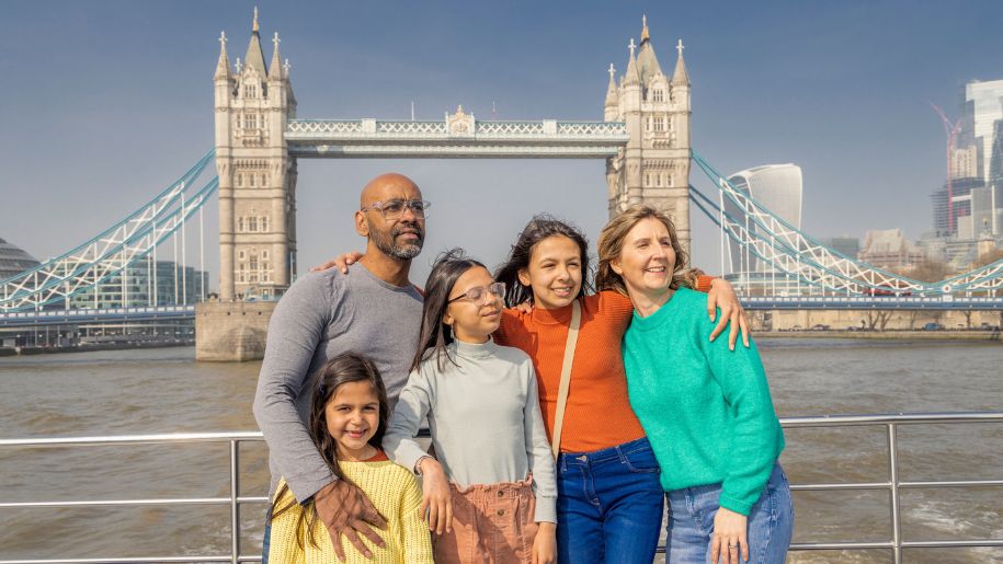 Family of 5 posing in front of London Bridge on a City Cruises boat