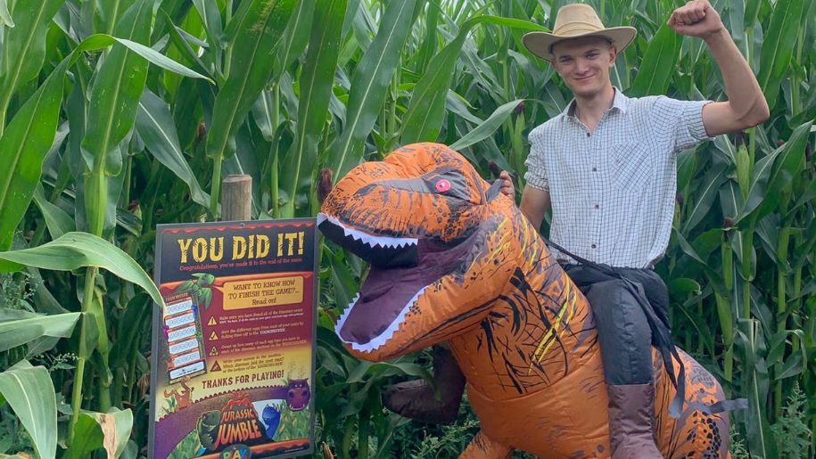 Man dressed in a dinosaur costume outside the dino maze at Lower Drayton Farm