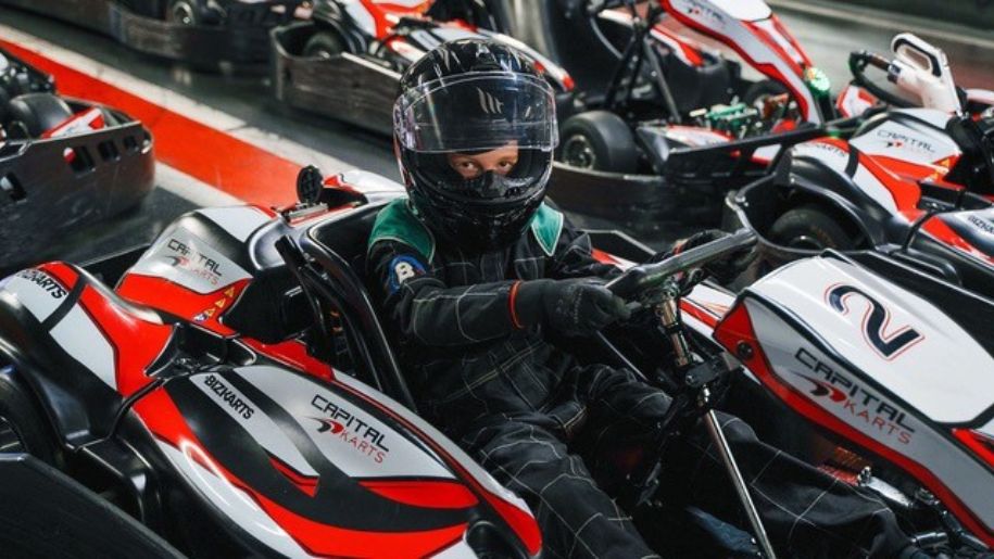 Boy in racing gear in a racking kart at Capital Kart