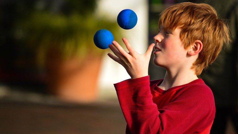 Boy wearing red top juggling balls