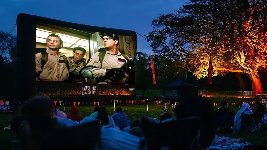 Open-air cinema screen showing film 'Ghostbusters' for Halloween.