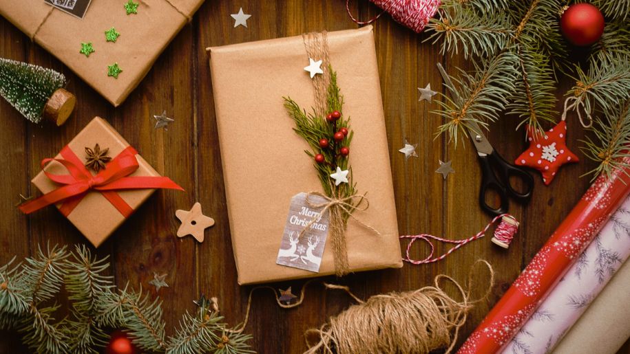 Christmas presents wrapped in brown paper and decorated with stars and greenery.