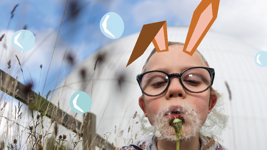 Winchester Science Centre Child with rabbit ears blowing on a dandelion