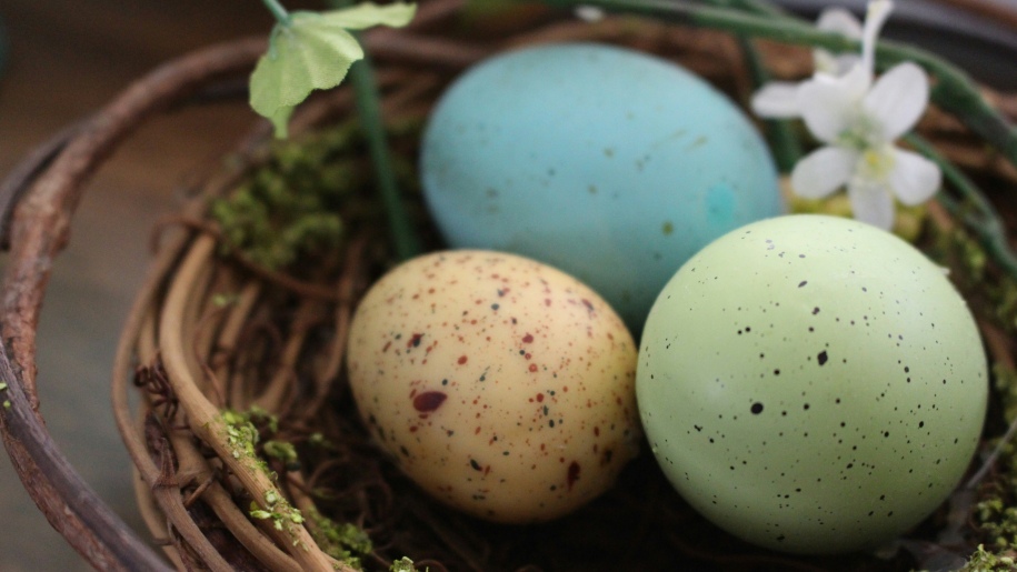 Three large coloured eggs in a basket.