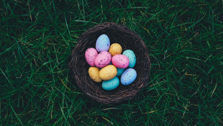 Blue, pink and yellow speckled Easter eggs in a small basket.