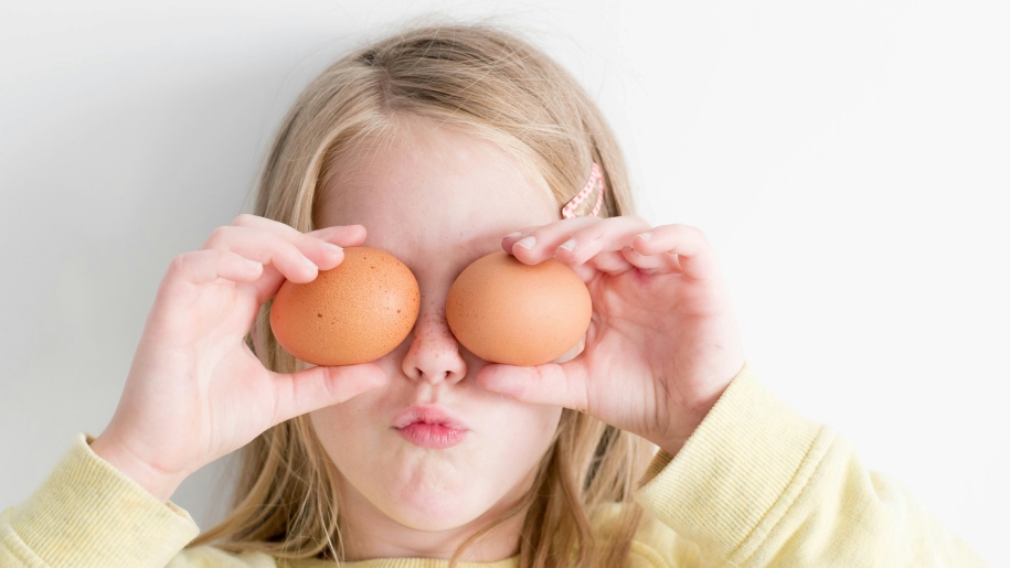 A child holding eggs in front of her face.