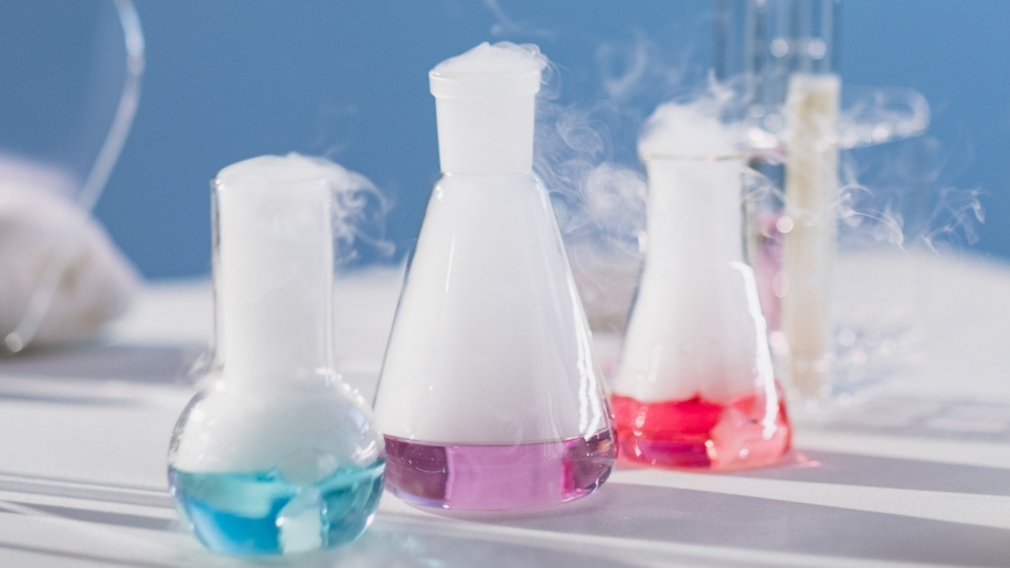 Three science beakers containing coloured liquids.