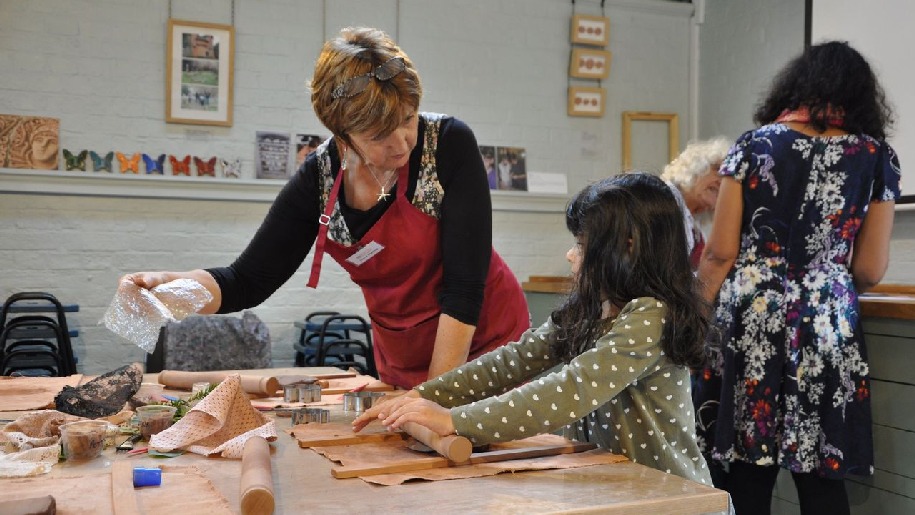 Watts Gallery Girl with rolling pin and teacher showing her what to do