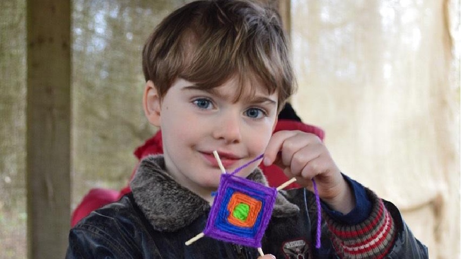 Celtic Harmony Camp Boy holding a woven wool square in four colours