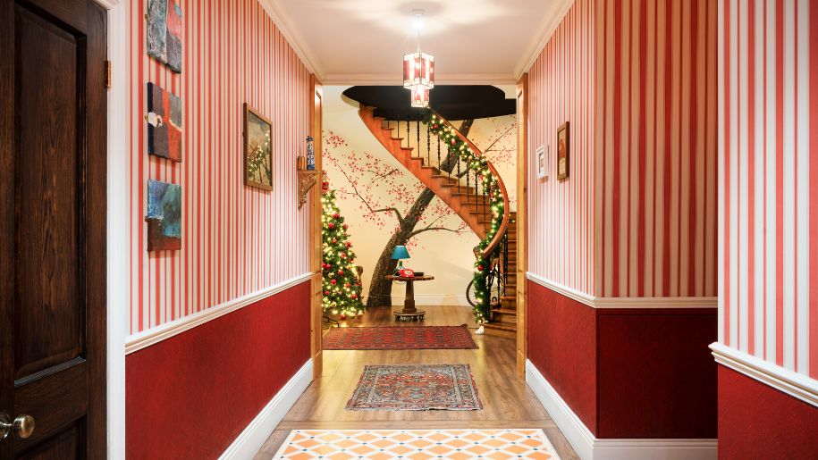 a hallway with red walls and red and white striped wallpaper, leading to a curved stairway