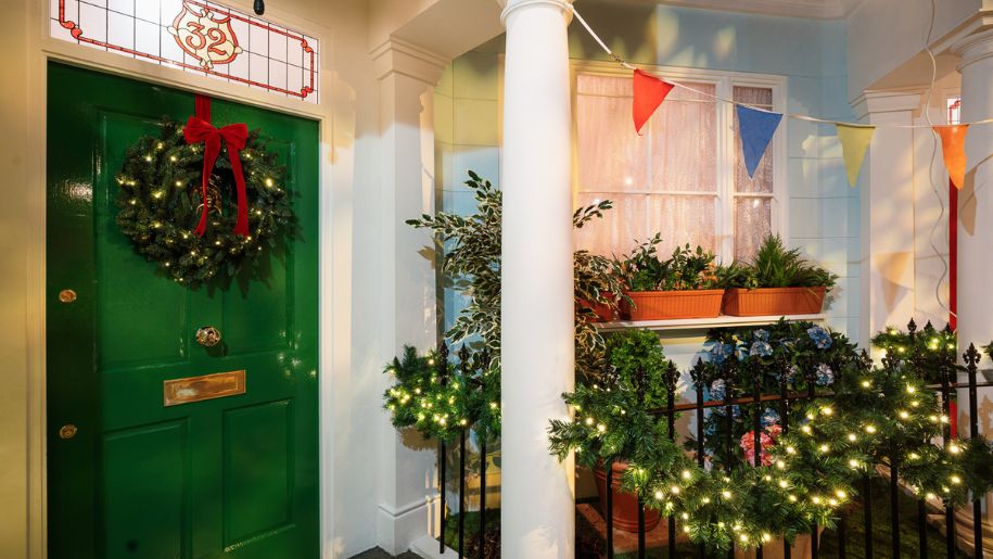 green door with christmas reef and a green light up garland on a fence