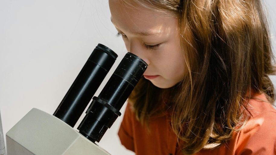 Child studying something under a microscope.