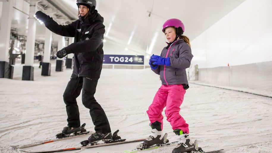 An instructor and child in ski's on the slopes at Snozone