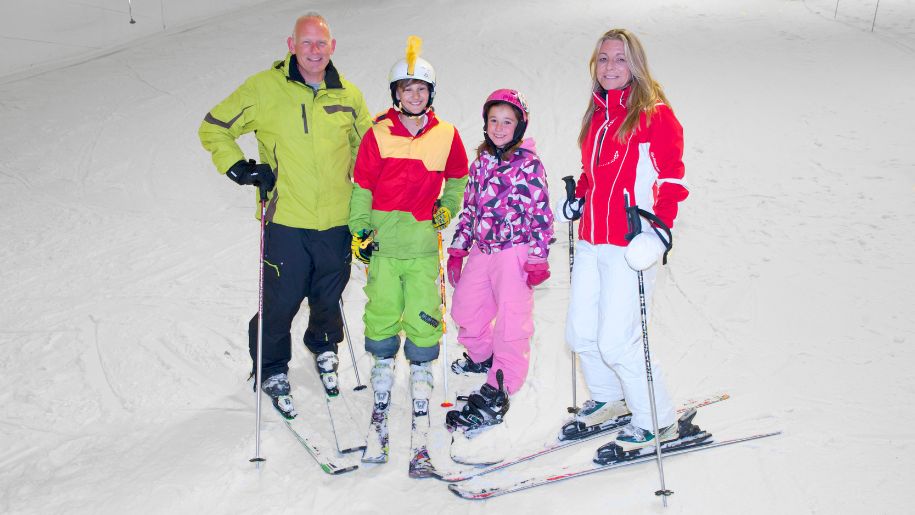 A family of 4 in ski wear on ski slopes at Snozone