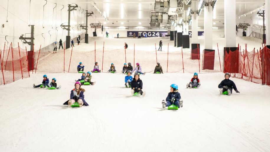 Multiple children sledding down a ski slope at Snozone