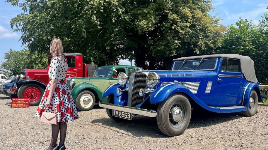 A women in 60's vintage clothing Infront of vintage cars at Watercress Line