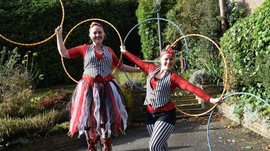 Circus performers holding hoops outside.