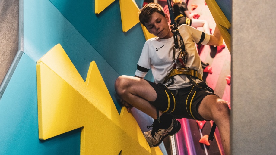 Child tackling a climbing wall at Crazy Climb Swansea.