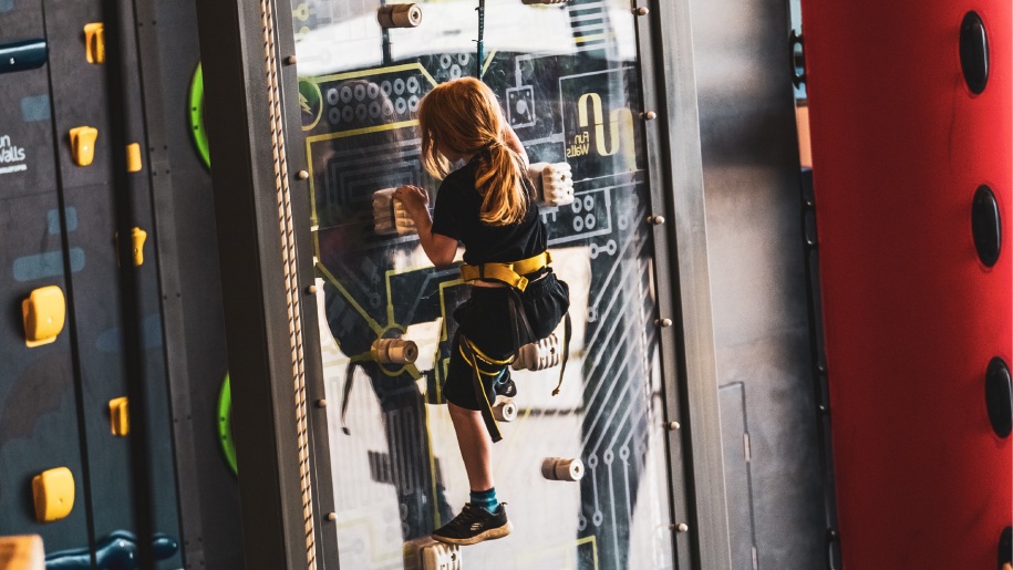 A child on a climbing wall at Crazy Climb Swansea.