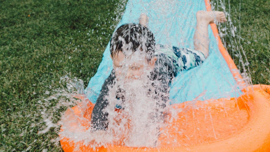 Child splashing in water at the end of a slip and slide.