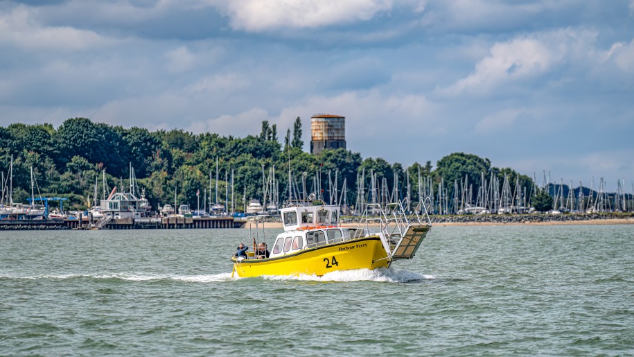 A yellow boat taking passengers on a ride around Harwich Harbour.