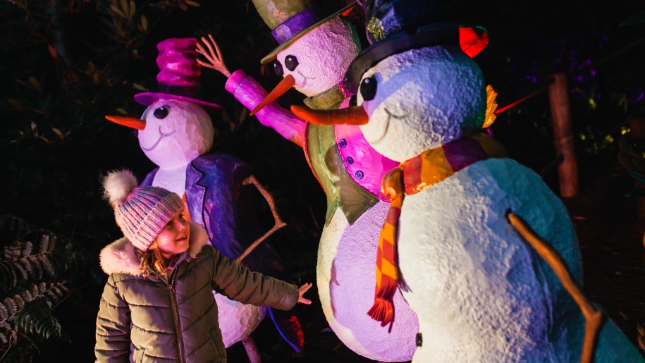 A child with three snowmen at BeWILDerwood's Christmas event.