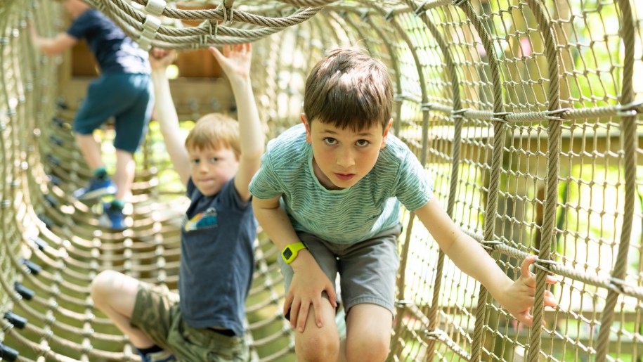 Children in a rope tunnel at Tumblestone Hollow adventure playground.