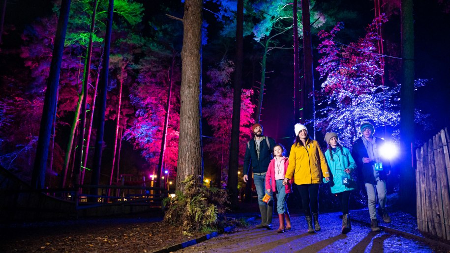 A family wandering along the magical Halloween light trail at BeWILDerwood.