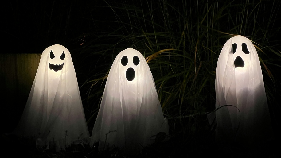 Three white Halloween ghosts in the dark.