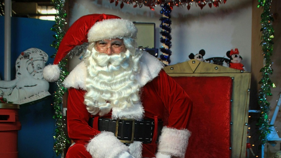 Santa sitting on a wooden chair in his grotto.