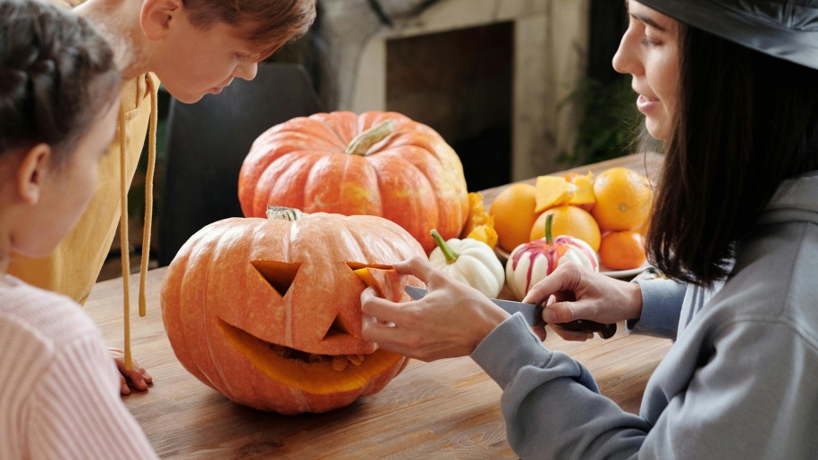 Mother and children carving a Halloween pumpkin.