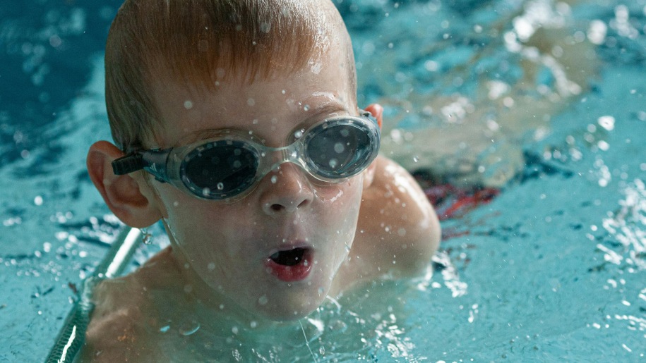 Child wearing goggles in a swimming pool.