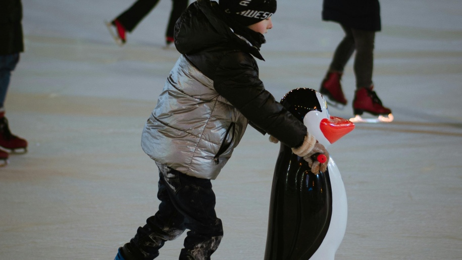 Child ice skating with a penguin skate aid.