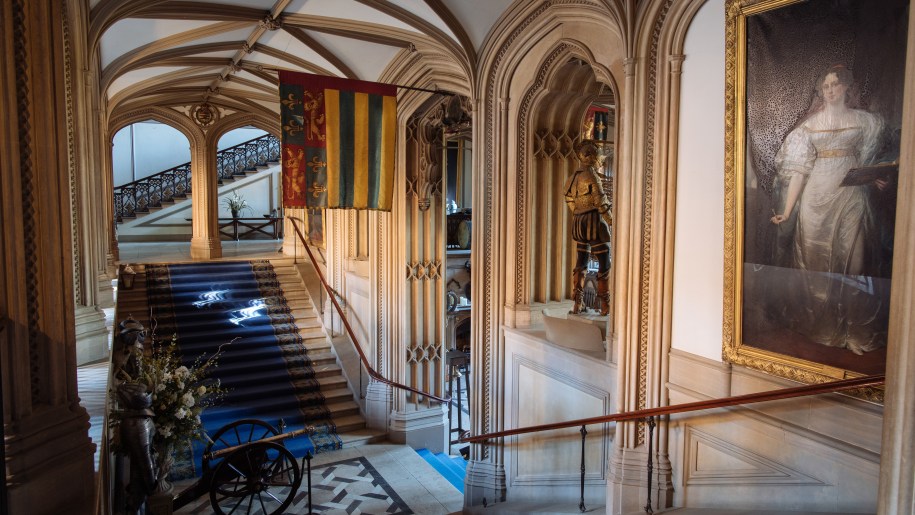 Staircase at Belvoir Castle with statue, portrait and flag.