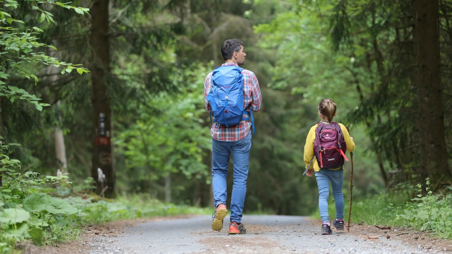 A father and daughter walking along a forest track.