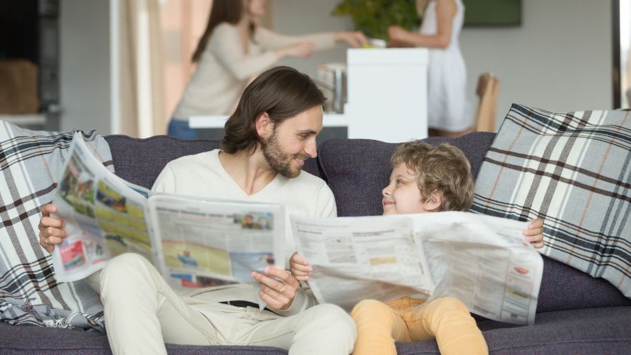 boy and dad reading a newspaper of a comfy sofa