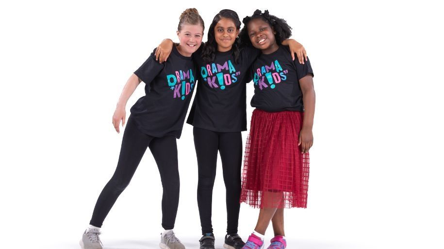 three drama kids smiling at the camera