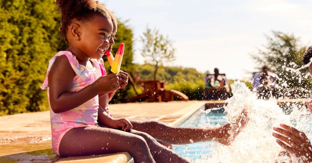 kid splashing in the pool eating ice lollies